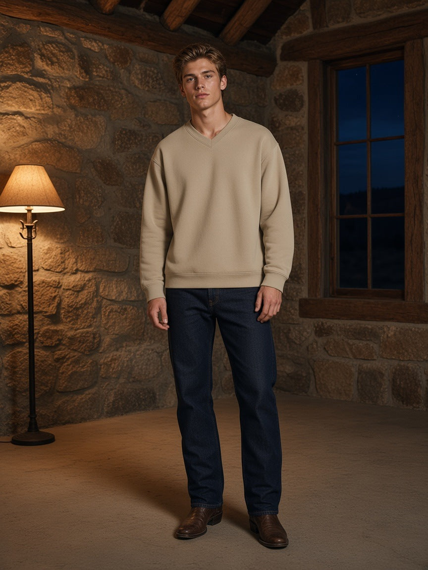 Marcel Afters Oversized V-Neck Sweatshirt in Khaki, worn by a man, stone wall