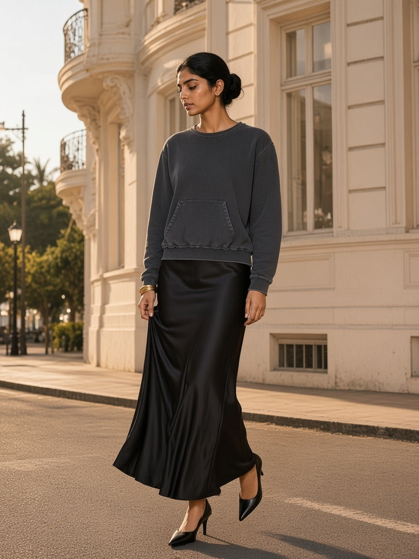Marcel Afters Raw Edge Crewneck Sweatshirt in Washed Gray, worn by a woman, walking a sunlit Paris street in a long satin skirt