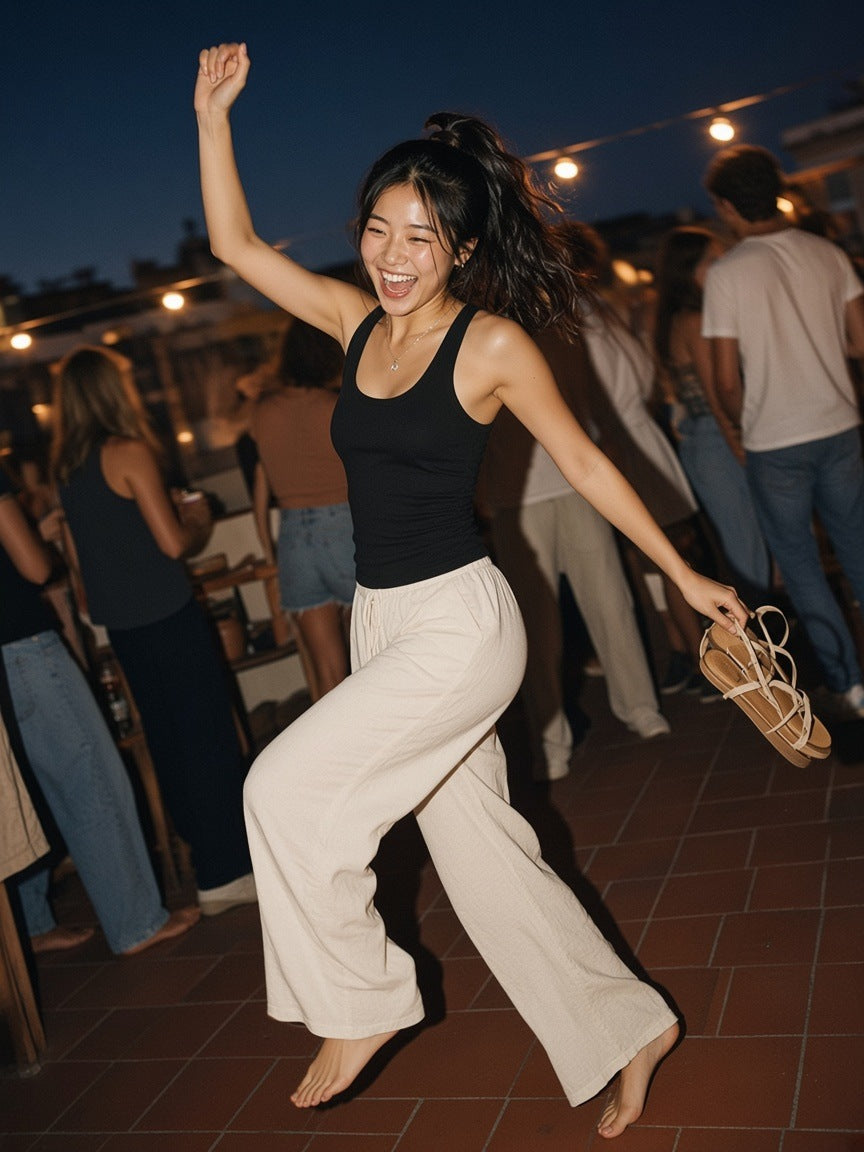 Woman in the Slim Fit Ribbed Racerback Tank Top in Black, dancing barefoot at a Barcelona rooftop party