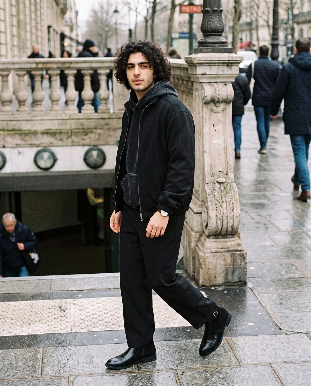 Man in Black snow wash hand-frayed heavyweight hoodie under a black jacket, on a rainy Paris street