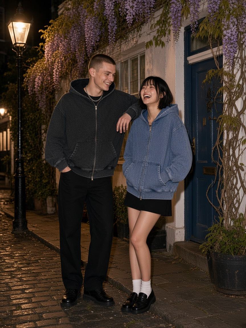 Marcel Afters Snow Wash Oversized Zip-Up Hoodie — Dark in Black, worn by a man and a woman, laughing together on a wisteria-lit cobbled lane at night