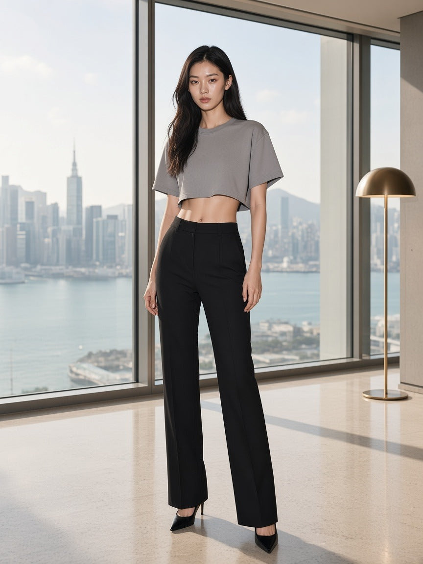 Marcel Afters Snow Washed Raw Edge Crop Top in Gray, worn by a woman, standing by a skyline window in a cropped grey tee and tailored black trousers