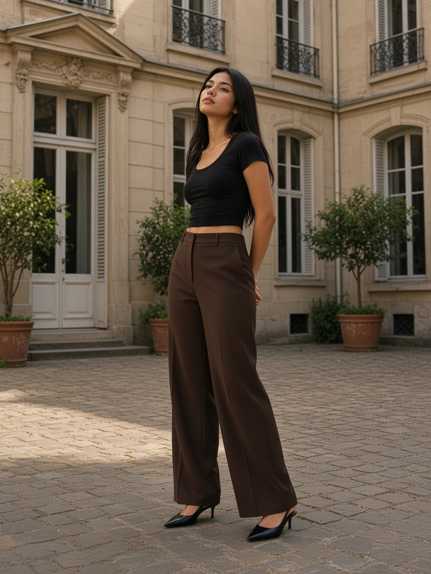 Woman in the Women's Solid Color Slim Crop T-Shirt in Black with chocolate wide trousers in a Paris mansion courtyard in the morning