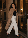 Woman in the Solid Color Straight-Leg Sweatpants in Oat Gray with a camel coat, stepping out of an old apartment building in Madrid at night