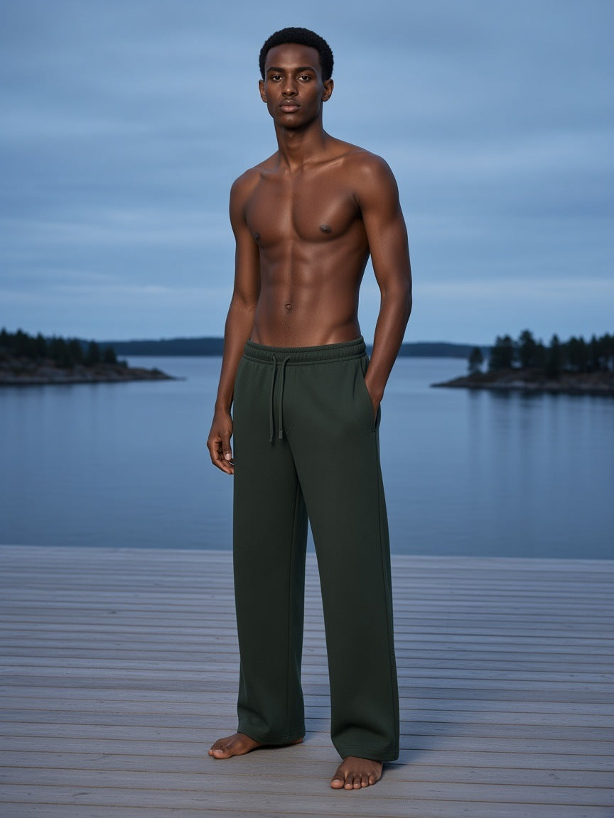 Marcel Afters Straight Leg Sweatpants in Blackish Green, worn by a man, on a dock