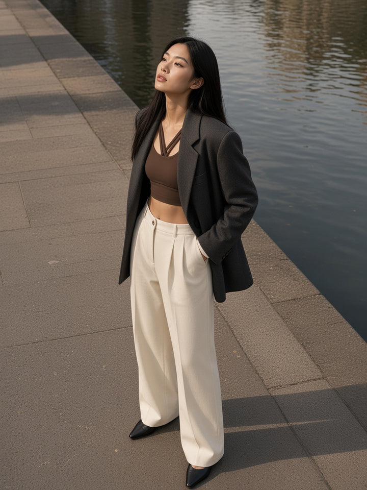 Marcel Afters Strappy Criss-Cross Sports Bra in Brown, worn by a woman, standing on a lakeside path in a grey blazer over a brown bra