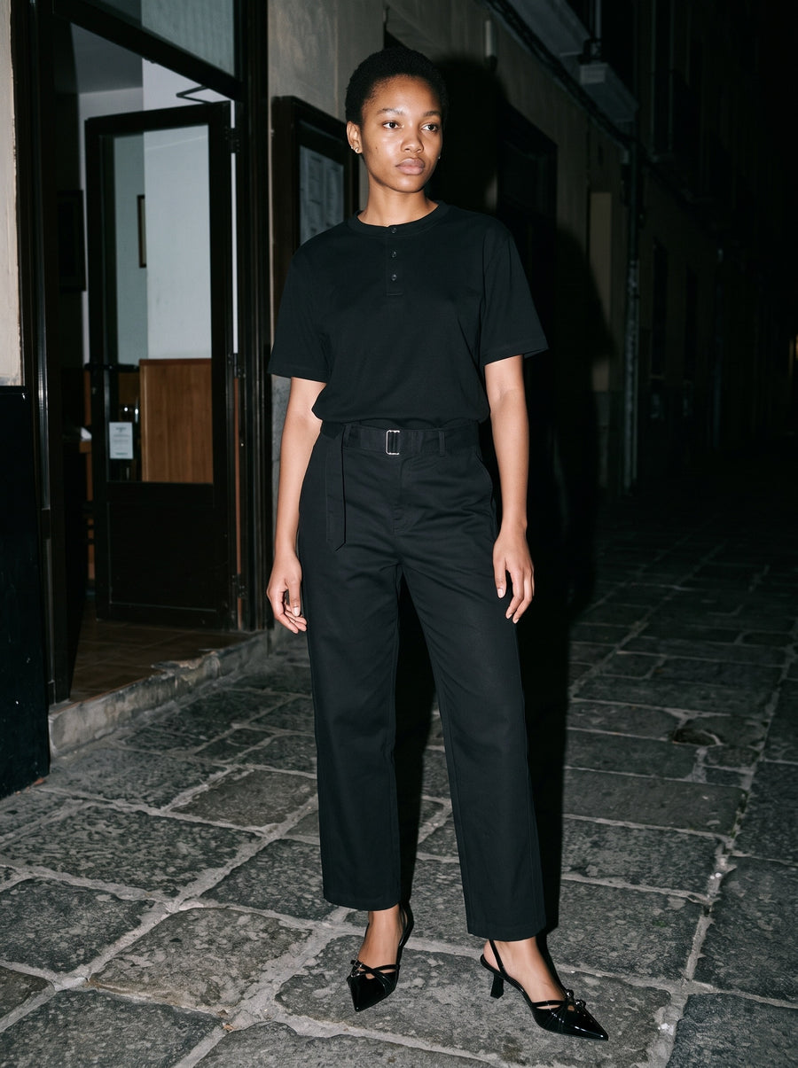 Woman wearing The After Six Slingback in Black with black belted barrel-leg cotton chino trousers and a black short-sleeve henley, flash photograph