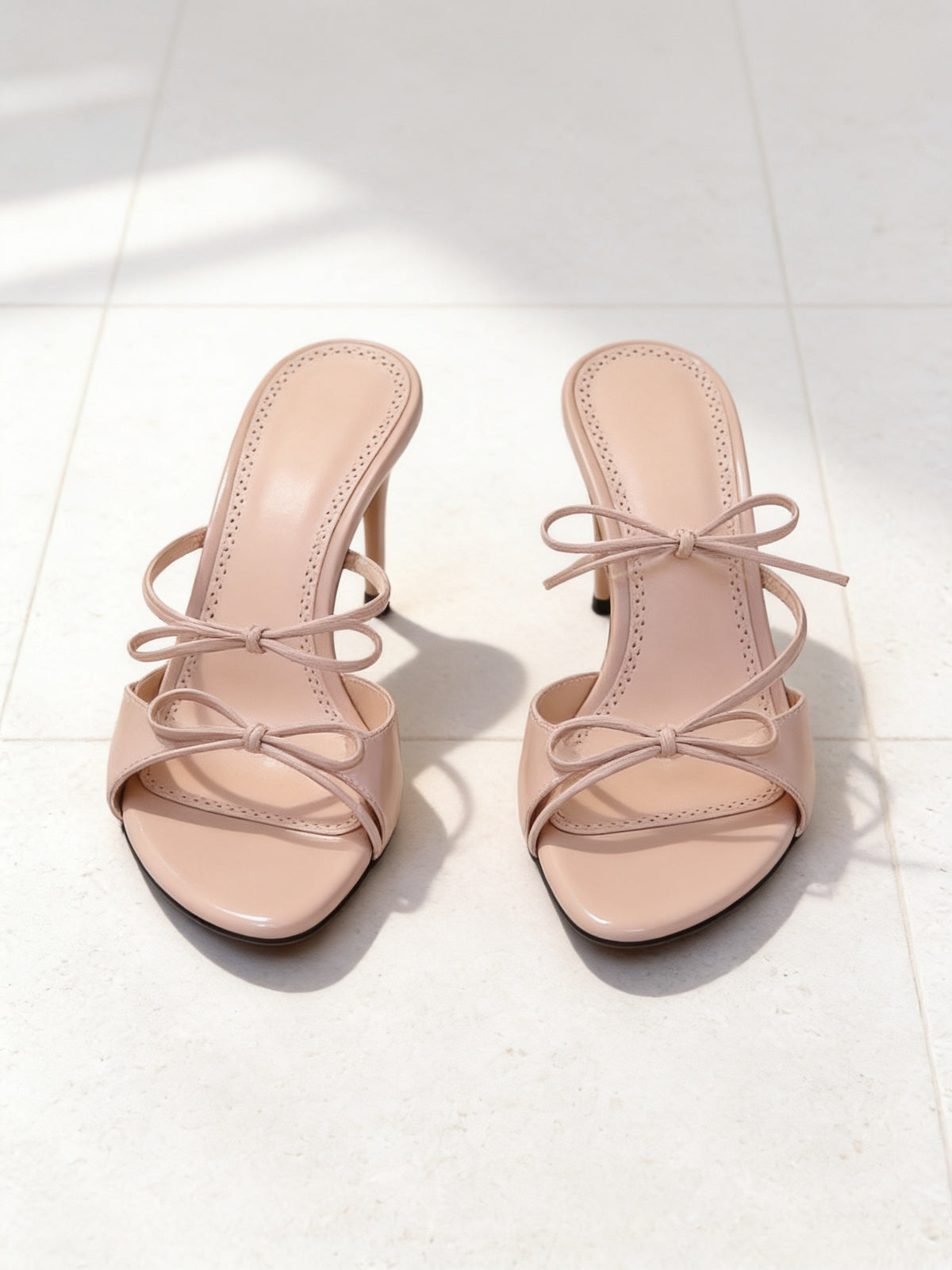 The Bow Tie Sandal in Nude, pair on pale limestone