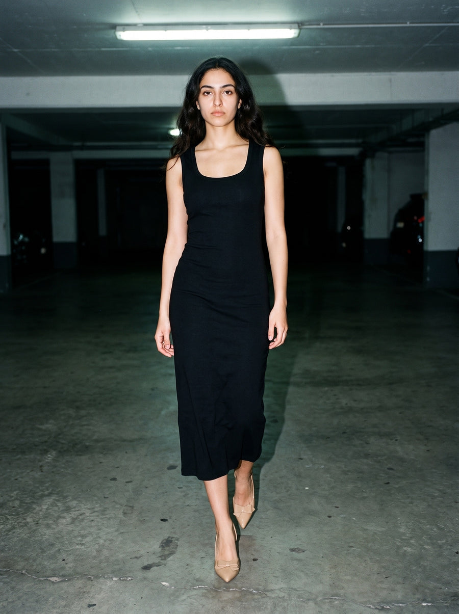 Woman wearing The Curtsy Pump in Nude with black scoop-neck sleeveless calf-length slim knit dress, flash photograph