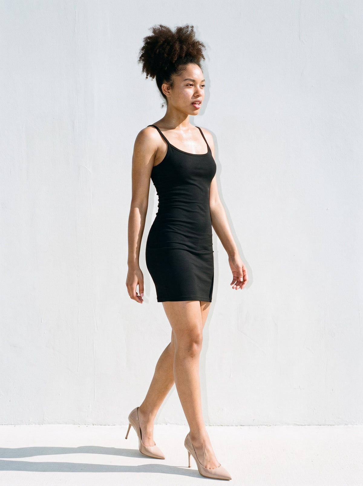Woman wearing The Guest of Honour Pump in Nude with black fine-strap close-fitting mini dress, flash photograph
