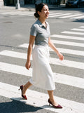 Woman wearing The Last Word Pump in Burgundy with white midi drawstring-waist jersey skirt and a gray fitted short-sleeve polo shirt, flash photograph