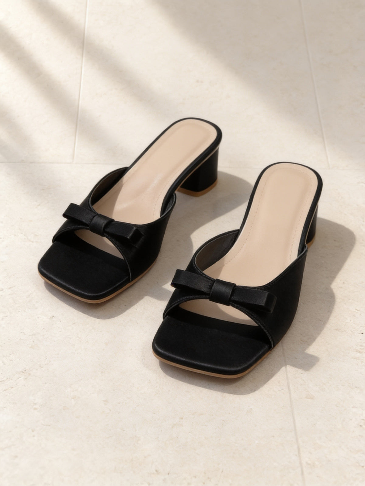 The Pillow Talk Mule in Black, pair on pale limestone