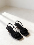 The Rooftop Sandal in Black, pair on pale limestone