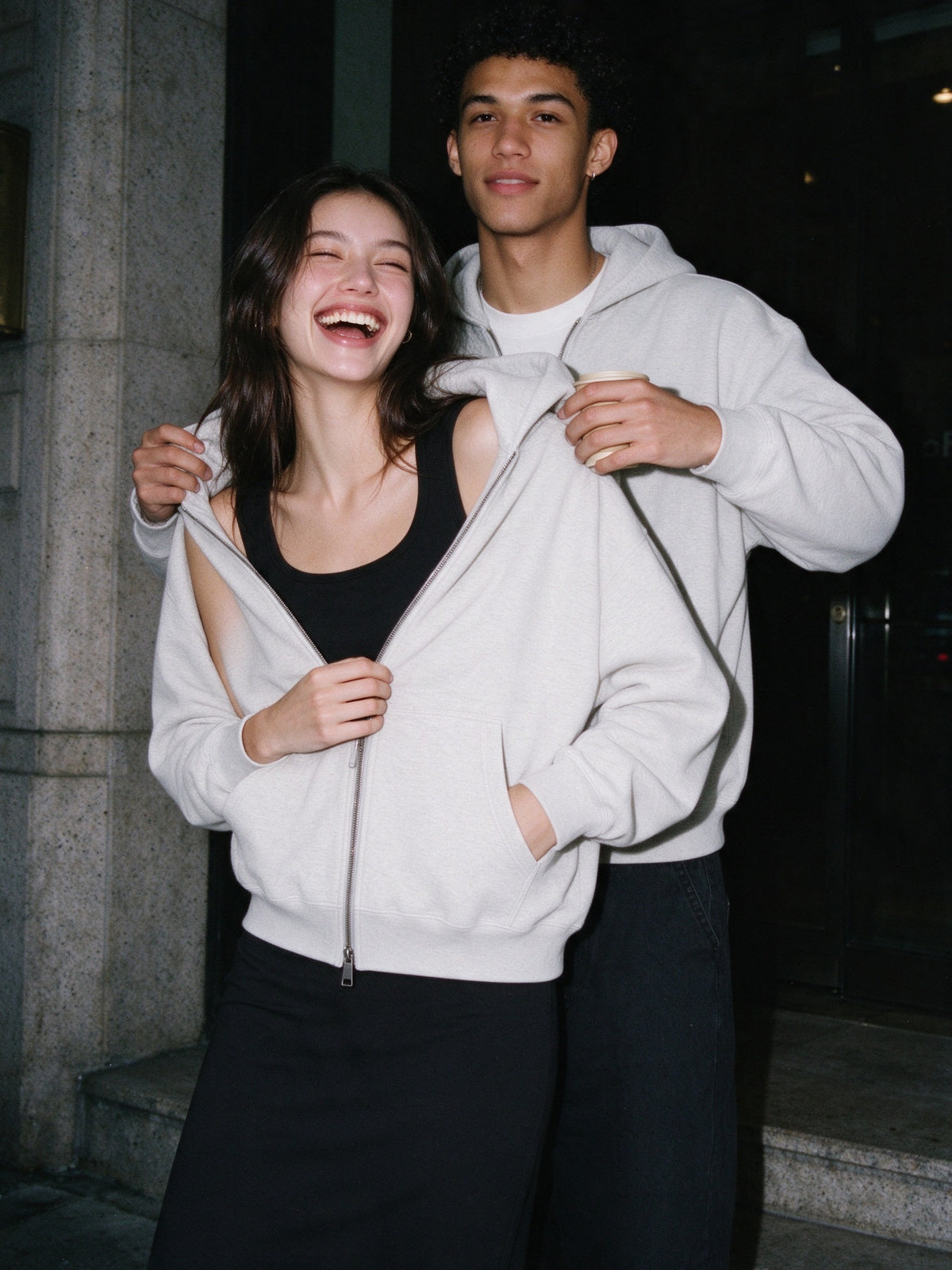 Woman wearing the Marcel Afters Heavyweight Full Zip Hoodie, Light Tones in Oat Gray, full-length editorial photograph
