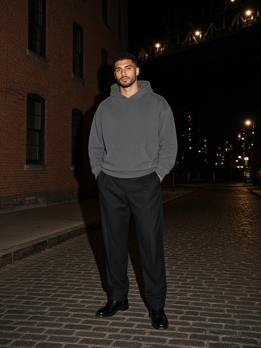 Marcel Afters Vintage Wash Boxy Hoodie in Dark Gray, worn by a man, standing on a cobbled street at night