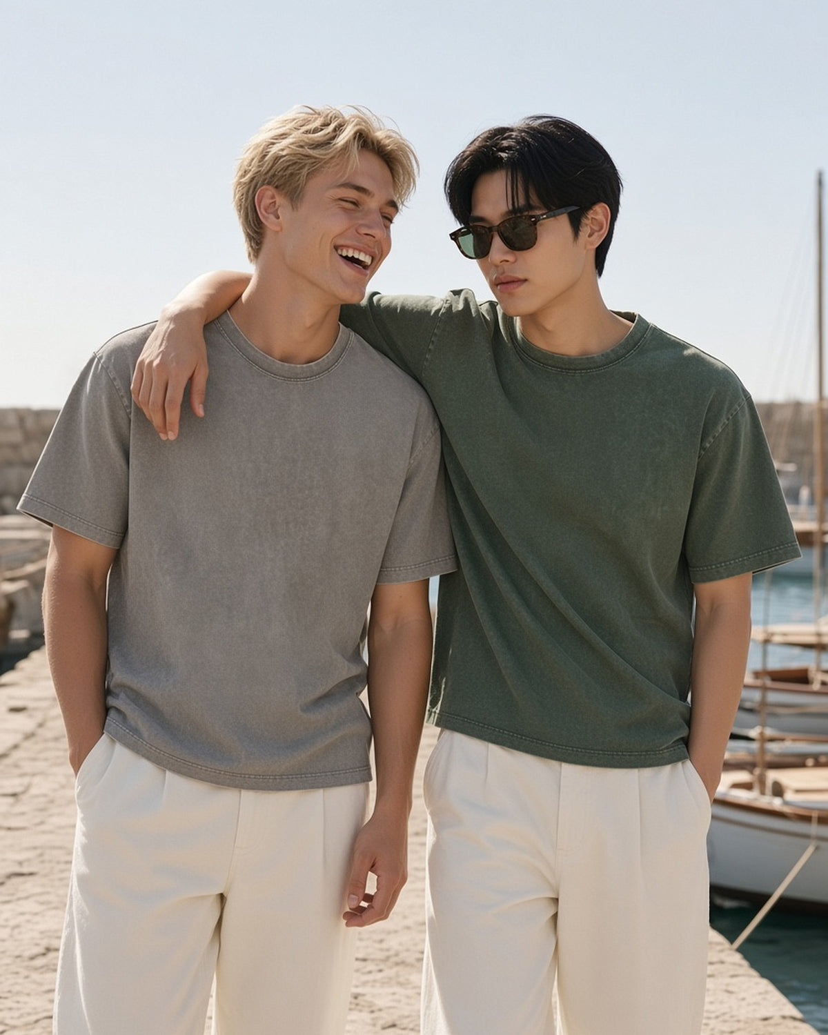 Two men in the Vintage Wash Boxy T-Shirt in Light Coffee and Army Green, arm in arm on a harbour jetty