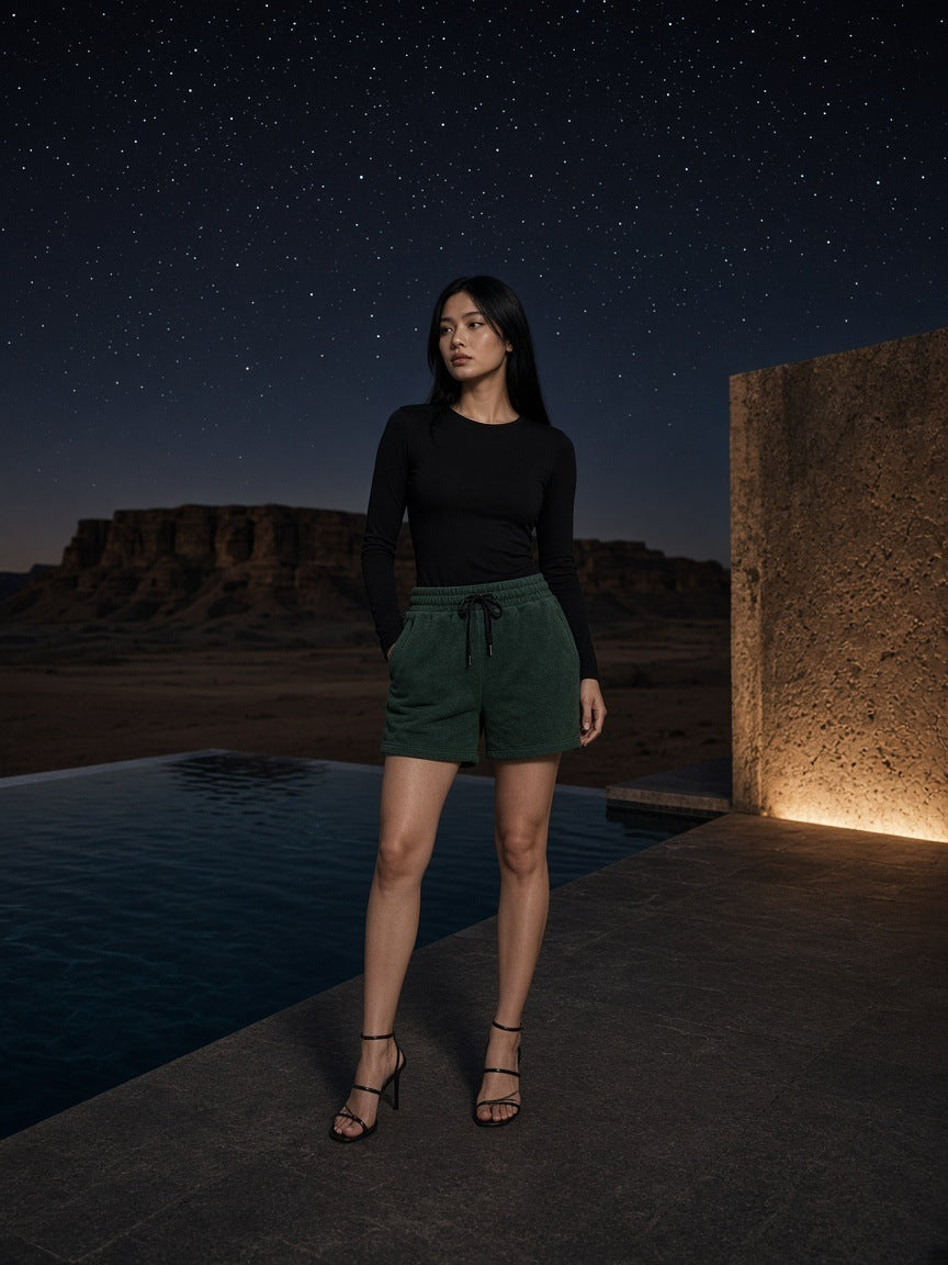 Marcel Afters Vintage Wash Fleece Shorts in Dark Green, worn by a woman, desert
