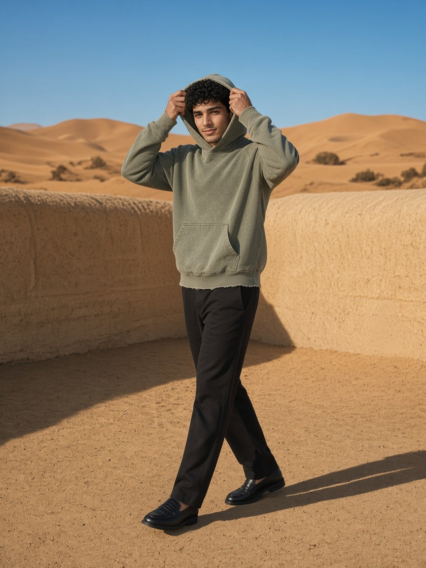 Marcel Afters Vintage Washed Frayed-Hem Hoodie in Army Green, worn by a man, walking through sand dunes in a washed sage hoodie