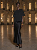 Woman in the Washed Rolled Hem Half Sleeve T-Shirt in Black, in a grand hotel's limestone courtyard at night in Paris