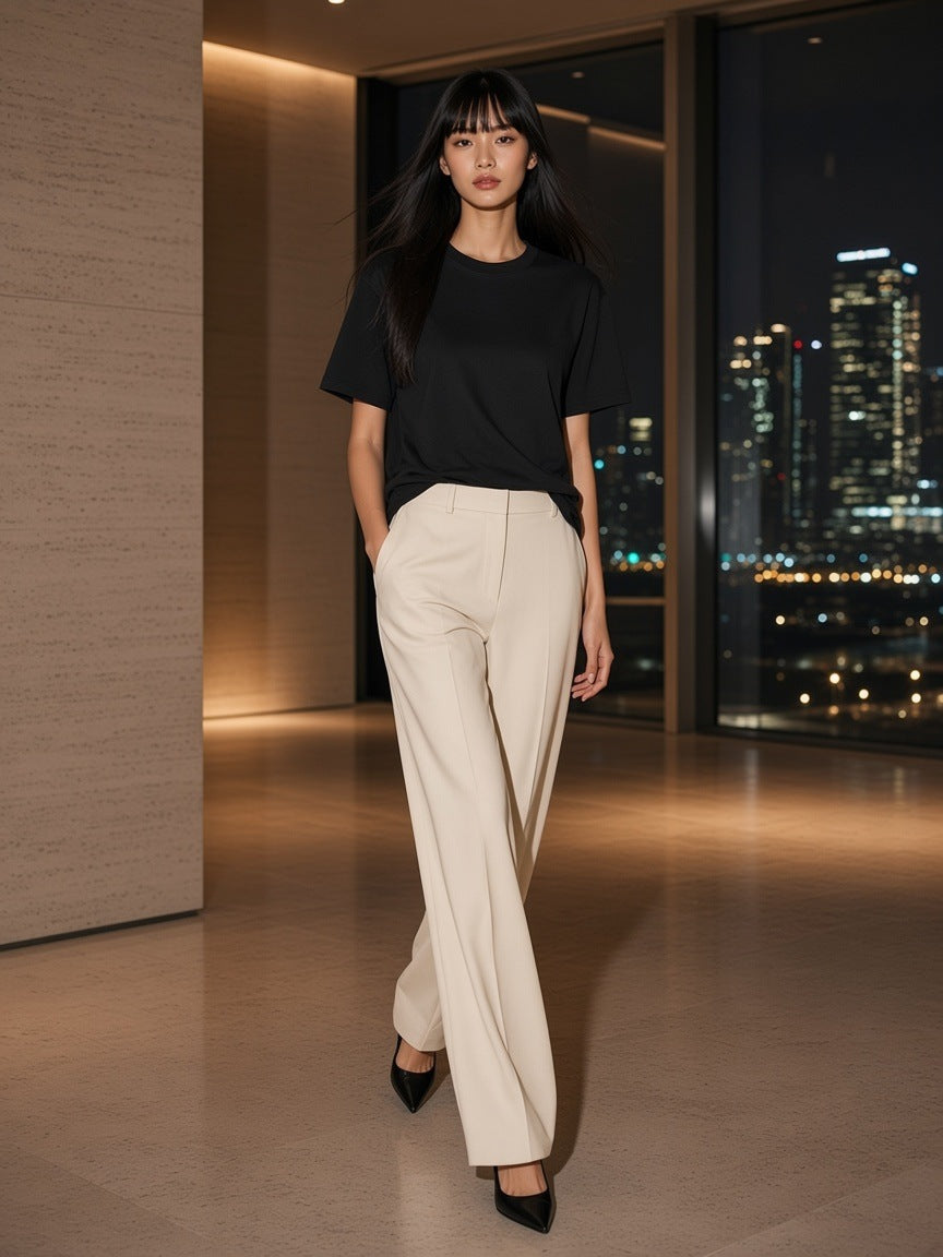 Marcel Afters Women's Essential Heavyweight Cotton T-Shirt in Black, worn by a woman, walking through a penthouse above the city at night