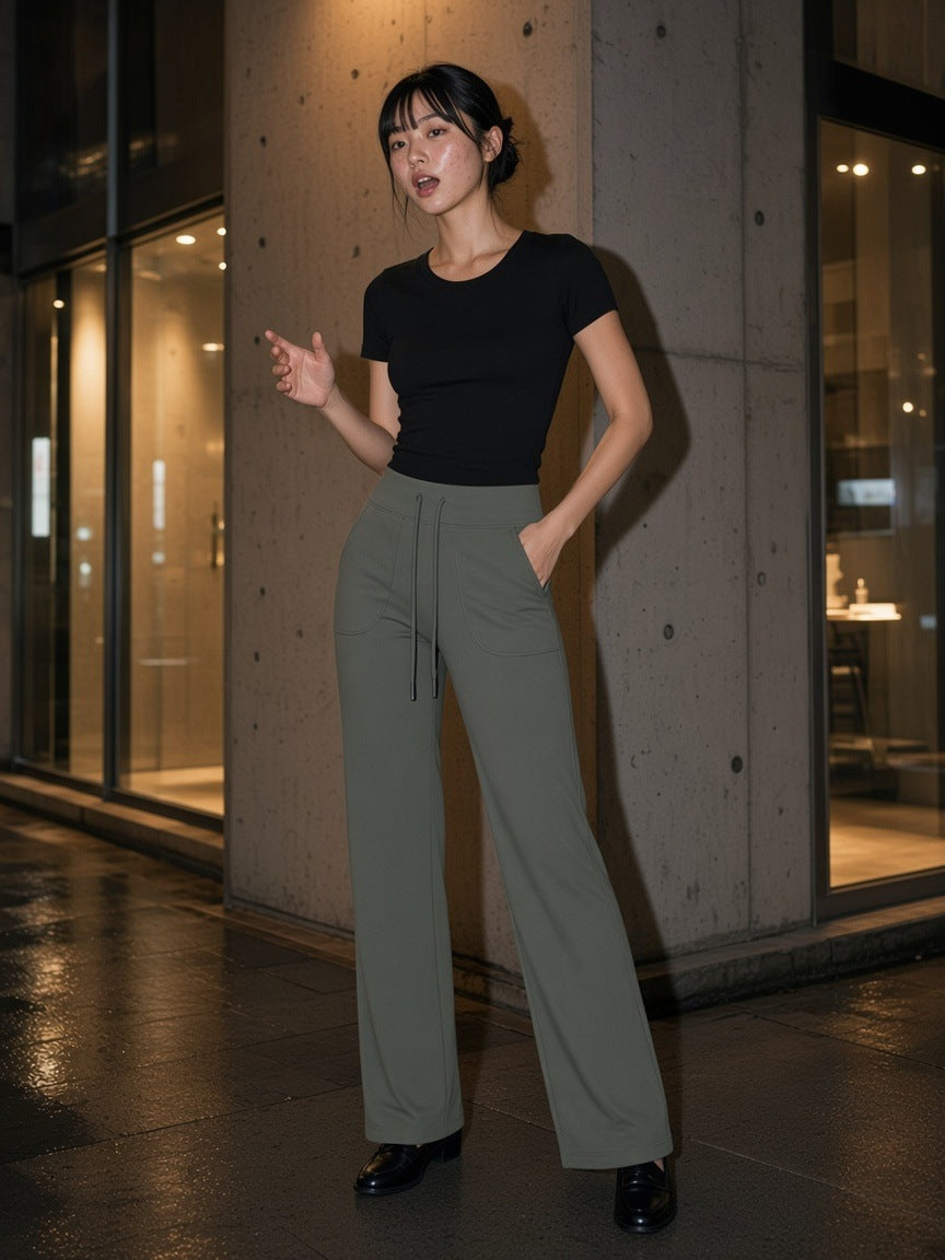 Woman in the High Rise Straight Leg Yoga Pants in Gray Green on a rain-wet corner in Aoyama, Tokyo at night