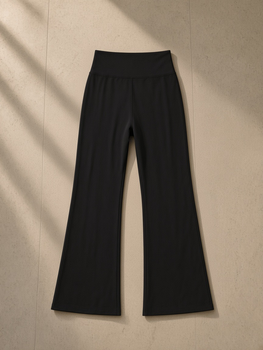 Women's High-Waisted Flare Leggings in Black, laid flat on pale limestone, back view