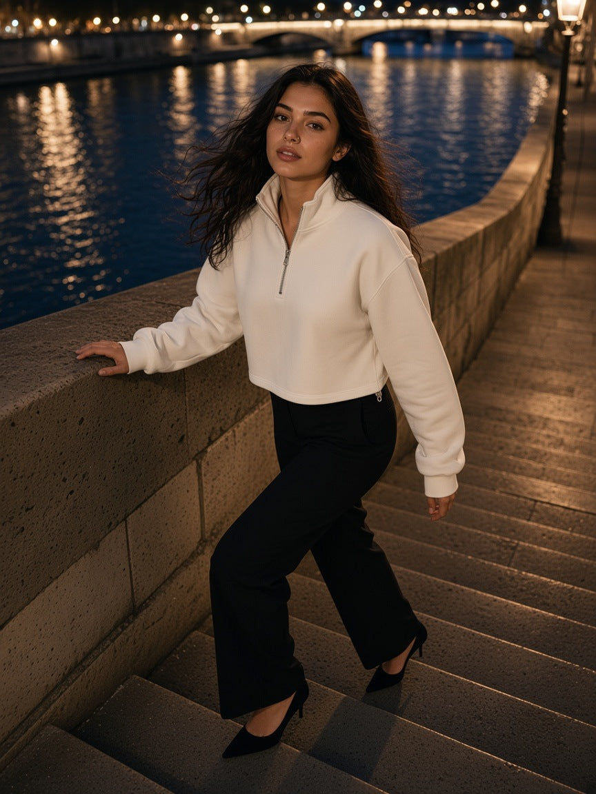 Woman in the Women's Mock-Neck Quarter-Zip Sweatshirt in White with black tailored trousers and kitten heels, climbing the stone steps to a Paris quai at night