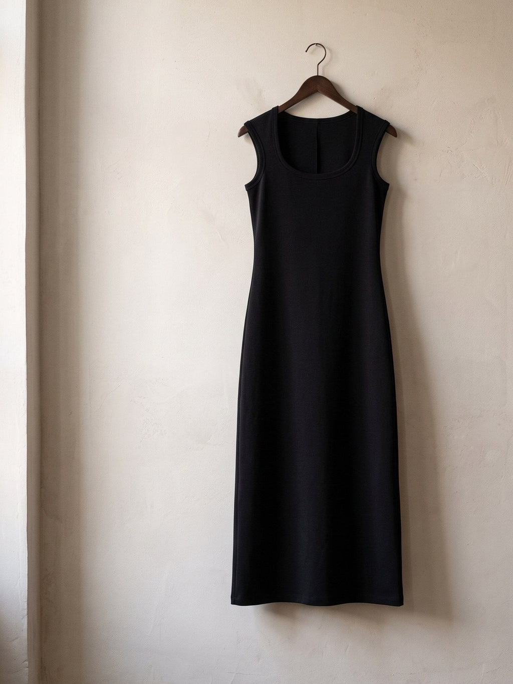 Women's Slim Sleeveless Dress in Black hanging on a plaster wall
