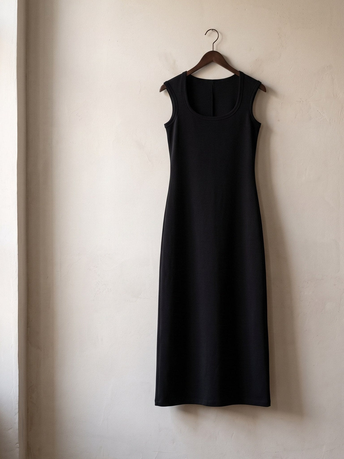 Women's Slim Sleeveless Dress in Black hanging on a plaster wall