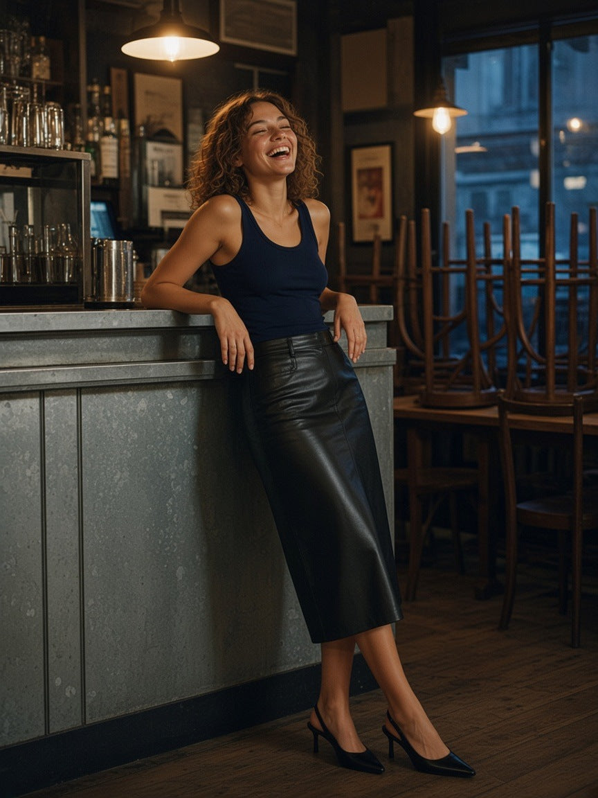 Woman in the Women's Slim Tank Top in Navy Blue with a black leather midi skirt and slingbacks, laughing against the counter of a Paris wine bar at closing