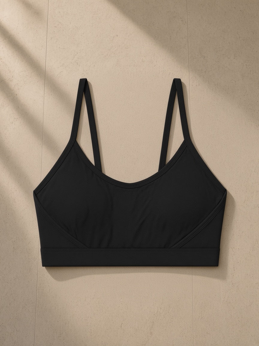 Women’s Tight Yoga Sports Bra in Black, laid flat on pale limestone, front view