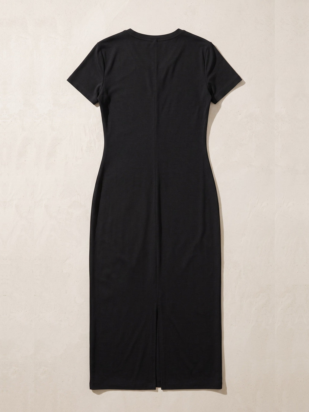 Women's V-Neck Short Sleeve Maxi Dress in Black laid flat on a warm stone surface, showing the V-neck, short sleeves and the long centre slit