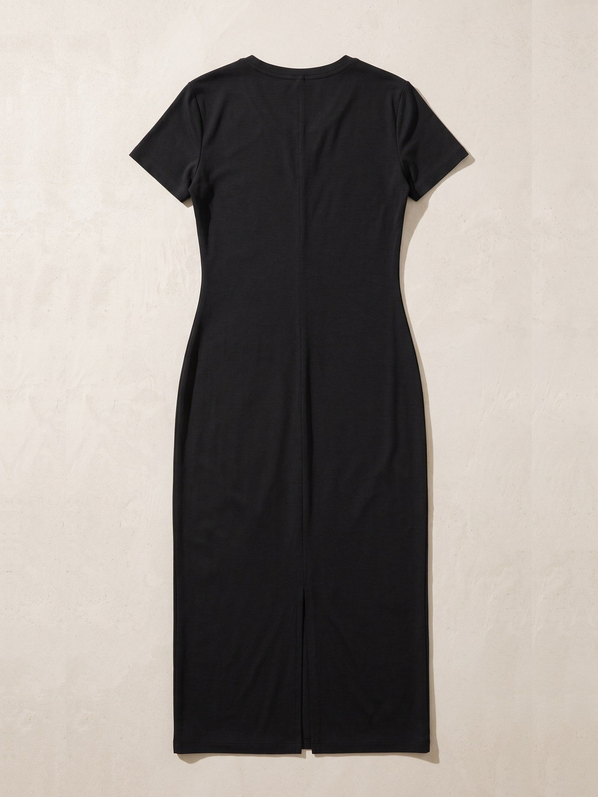Women's V-Neck Short Sleeve Maxi Dress in Black laid flat on a warm stone surface, showing the V-neck, short sleeves and the long centre slit