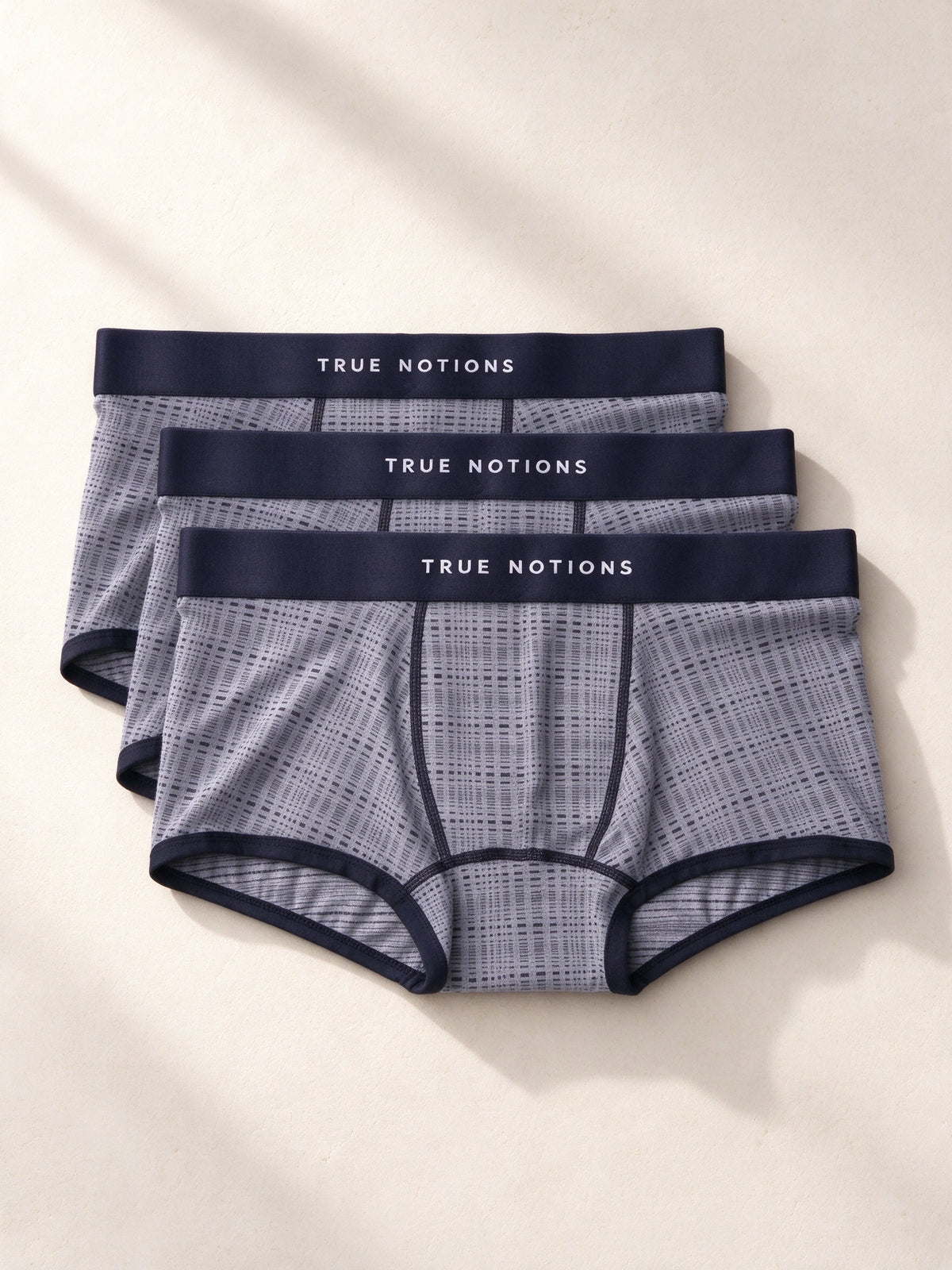 True Notions Tartan Trunks 3-Pack - Grey, laid flat on limestone
