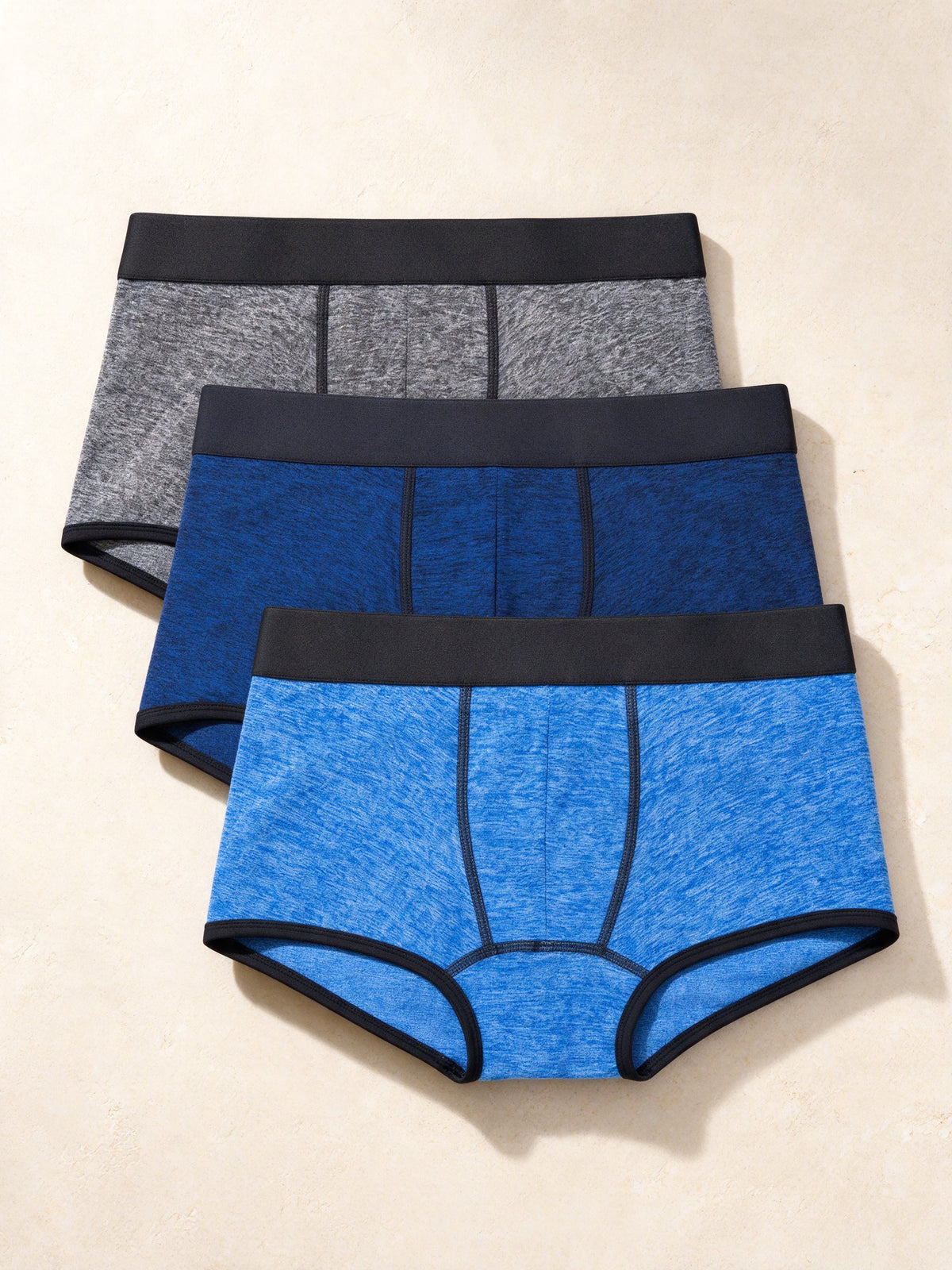 True Notions Trunks 3-Pack - Blue / Black, laid flat on limestone