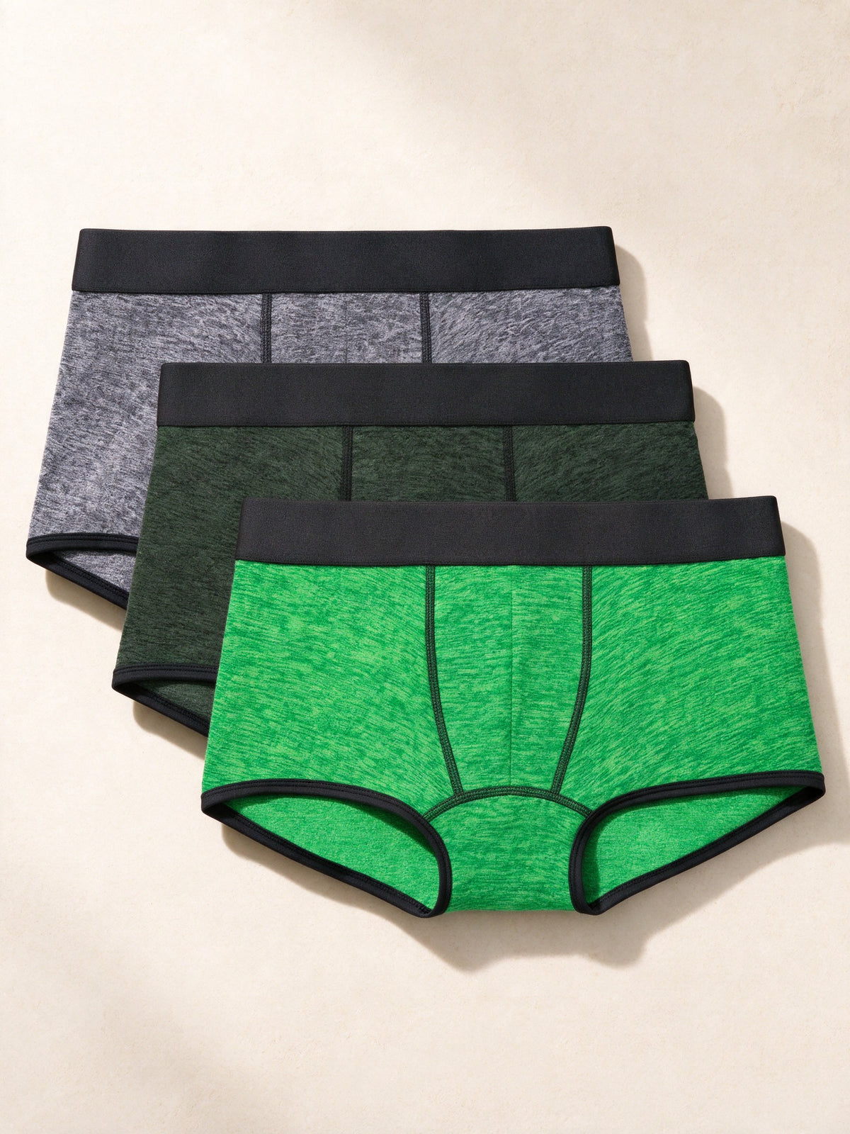 True Notions Trunks 3-Pack - Green / Black, laid flat on limestone