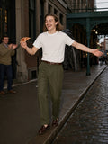 Man in the Men's Essential Heavyweight Cotton T-Shirt in White with olive trousers, balancing a curb with a pizza slice in lower Manhattan at dusk