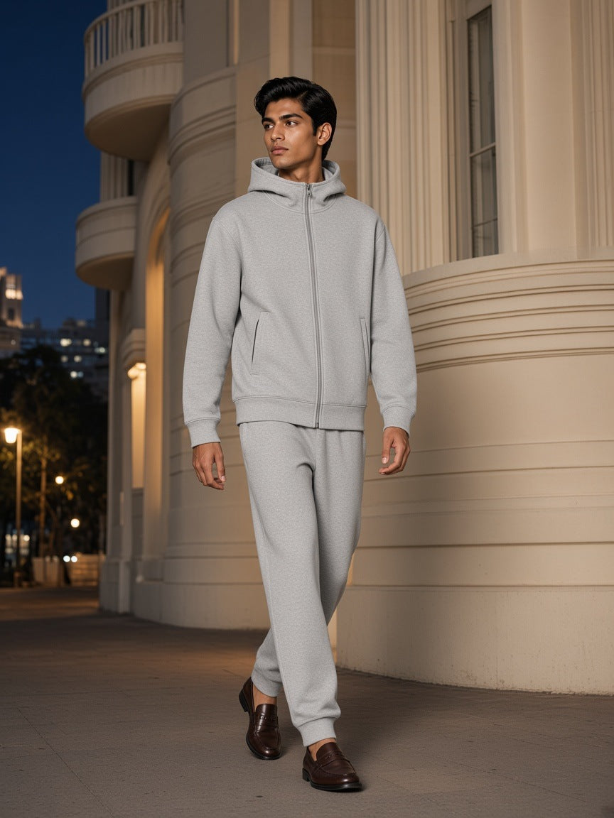 Man in the Men's Essential Heavyweight High Neck Zip-Up Hoodie in Flower Gray, walking past an Art Deco facade in Mumbai at night