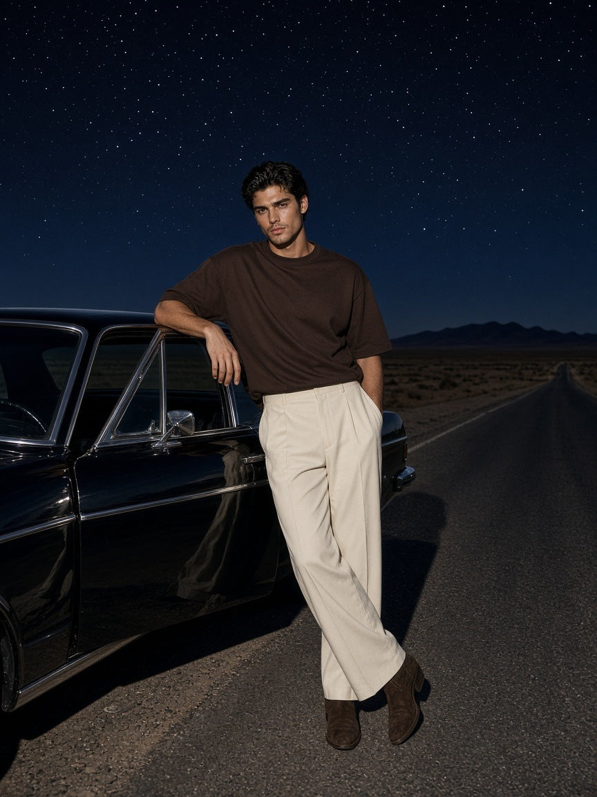 Man in the Men's Heavyweight Boxy T-Shirt in Coffee leaning on a black car on a desert road near Marfa at night