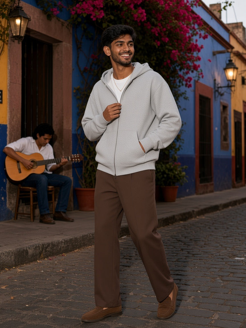 Man in a Flower Gray heavyweight full zip boxy hoodie on a colourful cobbled street at dusk