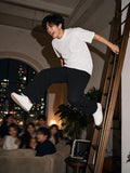 Man in the Men's Oversized T-Shirt in White with black trousers, leaping off a library ladder at a Tribeca loft party in New York at 1am