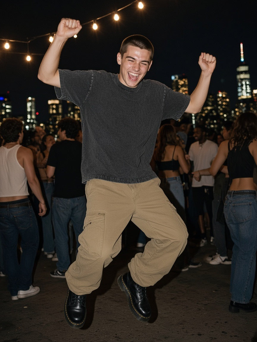 Man in the Men's Snow Washed Heavyweight Oversize T-Shirt in Olive Green on a rooftop over the Hudson in New York by day