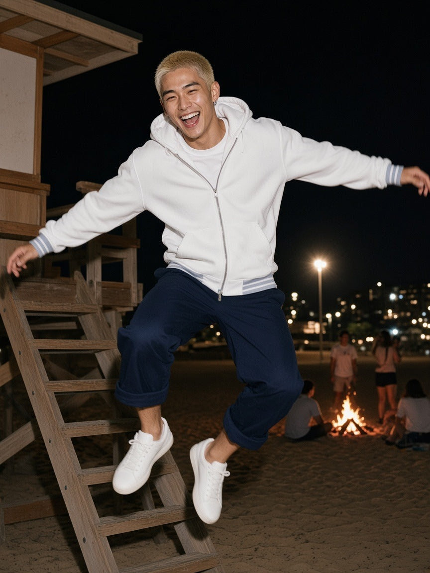Man in the Men's Striped Trim Zip-Up Hoodie in White, leaping off a lifeguard-tower ramp at Bondi at 1am