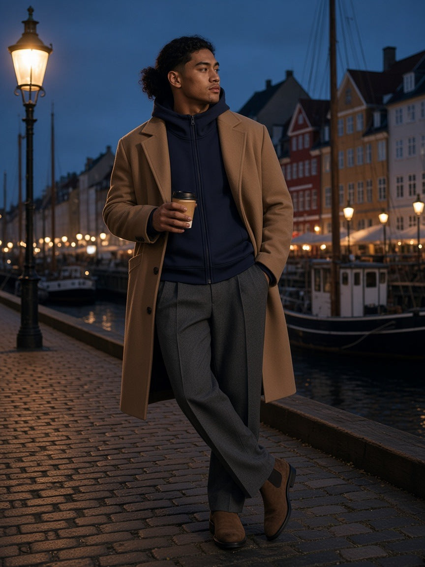 Man in the Men's Essential Heavyweight High Neck Zip-Up Hoodie in Navy Blue with a coffee on Nyhavn quay in Copenhagen at night
