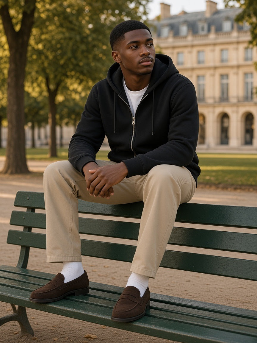 Man in the Men's Heavyweight Full Zip Hoodie in Black sitting on a Tuileries bench at golden hour
