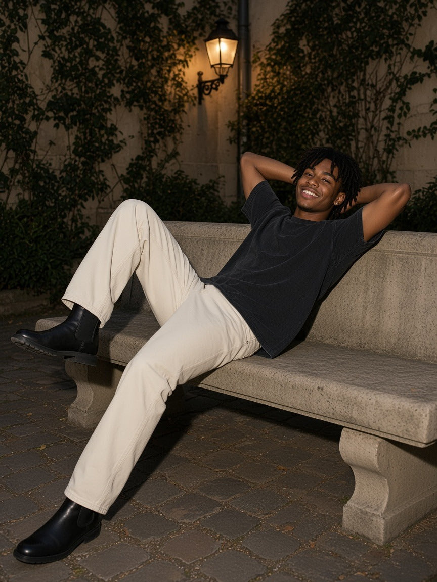 Man in the Men's Heavyweight Mineral Wash Boxy T-Shirt in Black lying on a stone bench in a Paris courtyard at night