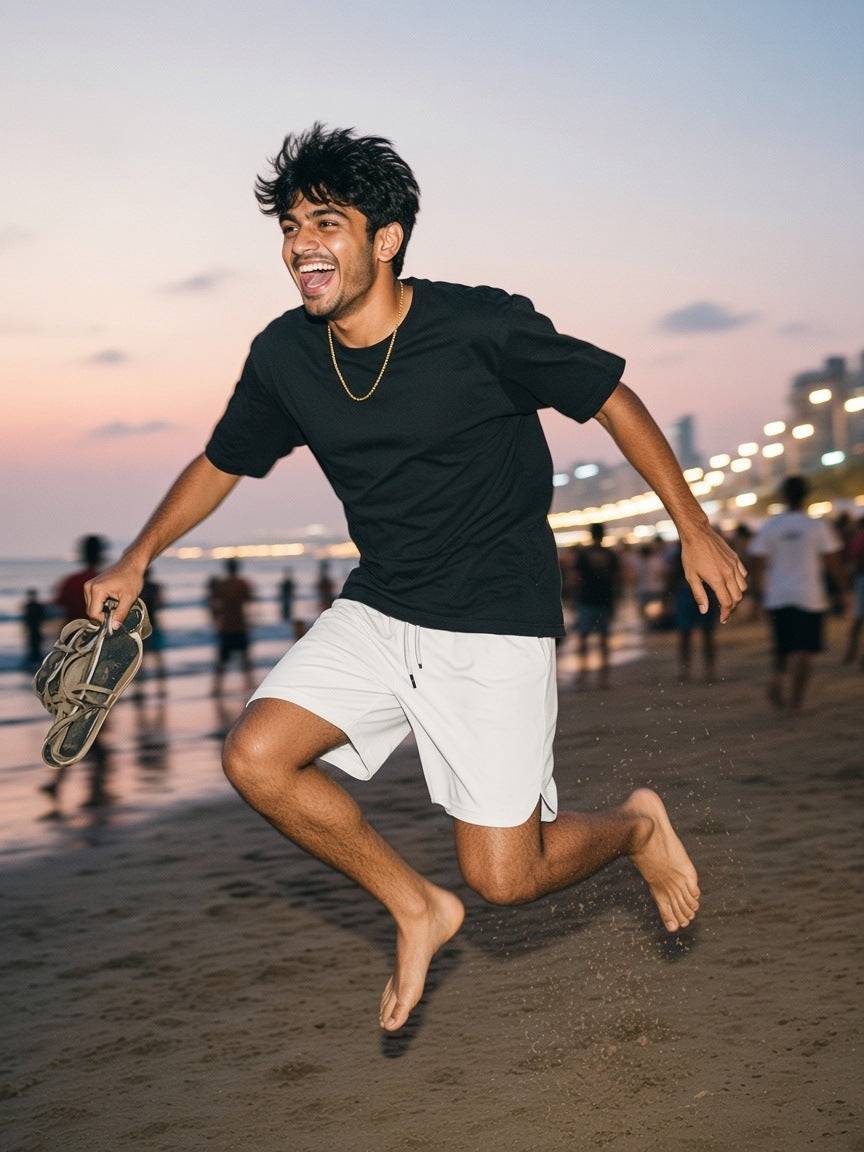 Man in the Mesh-Lined Quick-Dry Shorts in Grayish White, running barefoot on a Mumbai beach at dawn after a night out