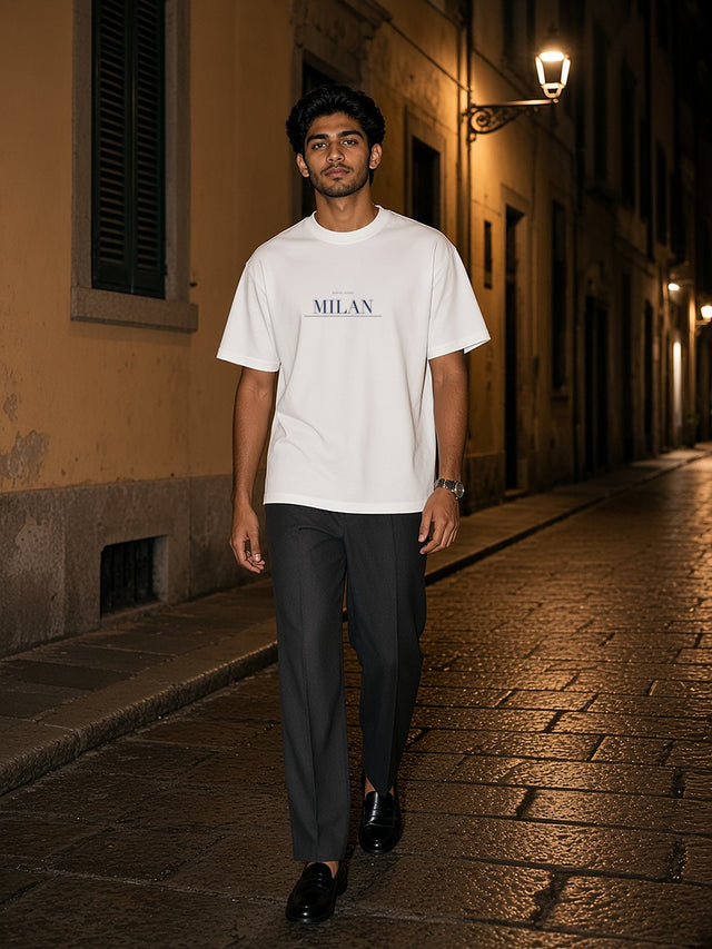 Man in the Milan tee in White walking down a lamplit Brera side street in Milan after dark
