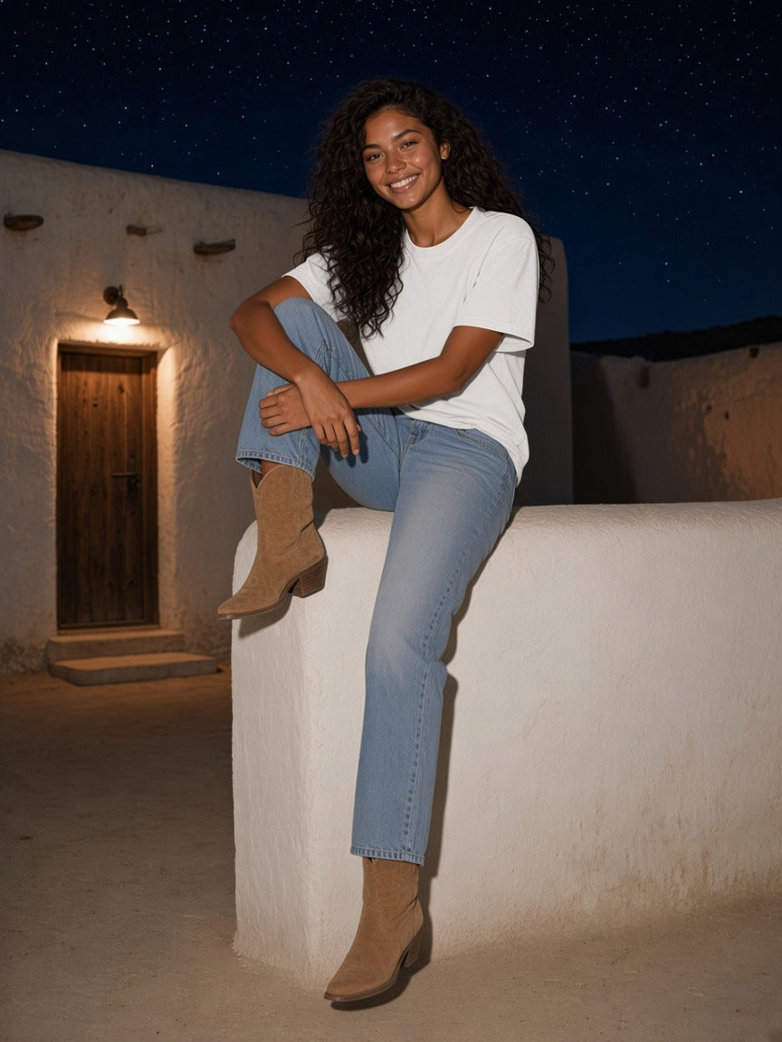 Woman in the Mineral Wash Boxy Cotton T-Shirt in White with light jeans, perched on a whitewashed wall under the stars