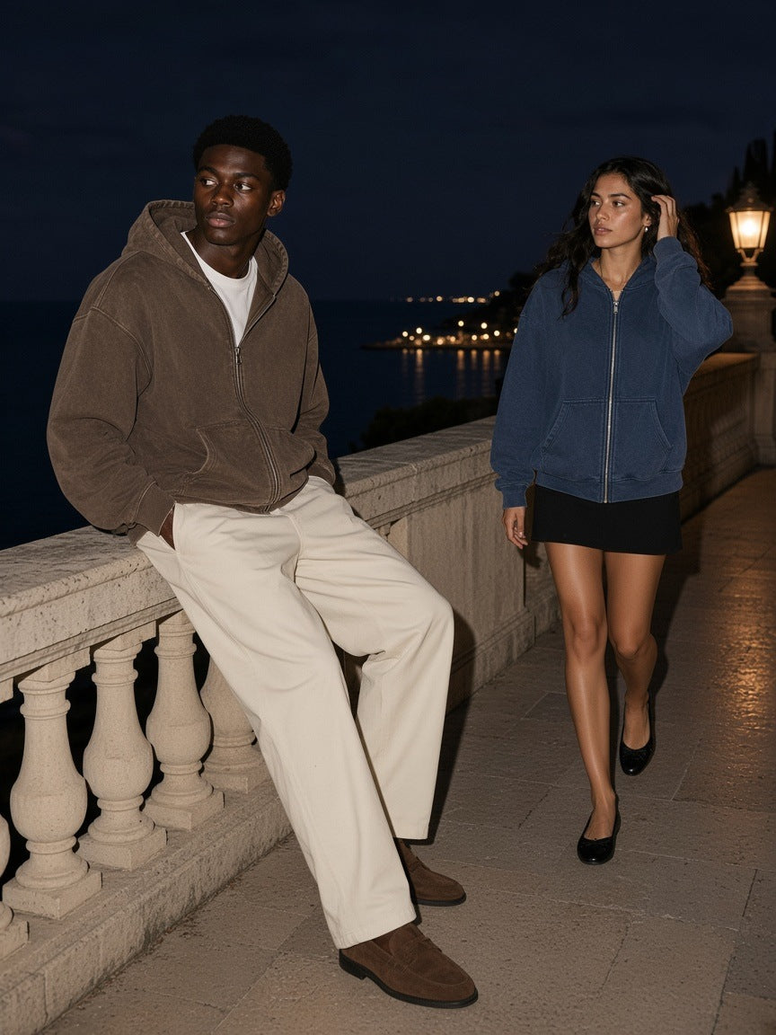 Man and woman in the Mineral Wash Boxy Full Zip Hoodie in Coffee and Navy Blue on an empty stone terrace above the Riviera at night
